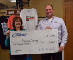 Mark Denn presenting donation check to Madelia Chamber of Commerce for Madelia Strong.